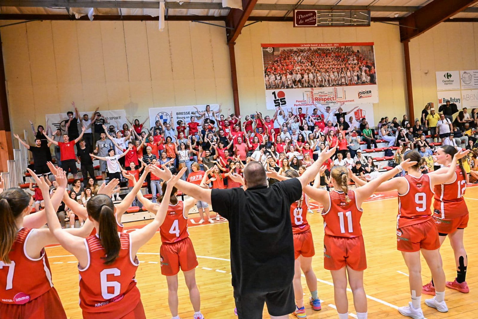 Joueuses et coach saluent leurs supporters, bras levés