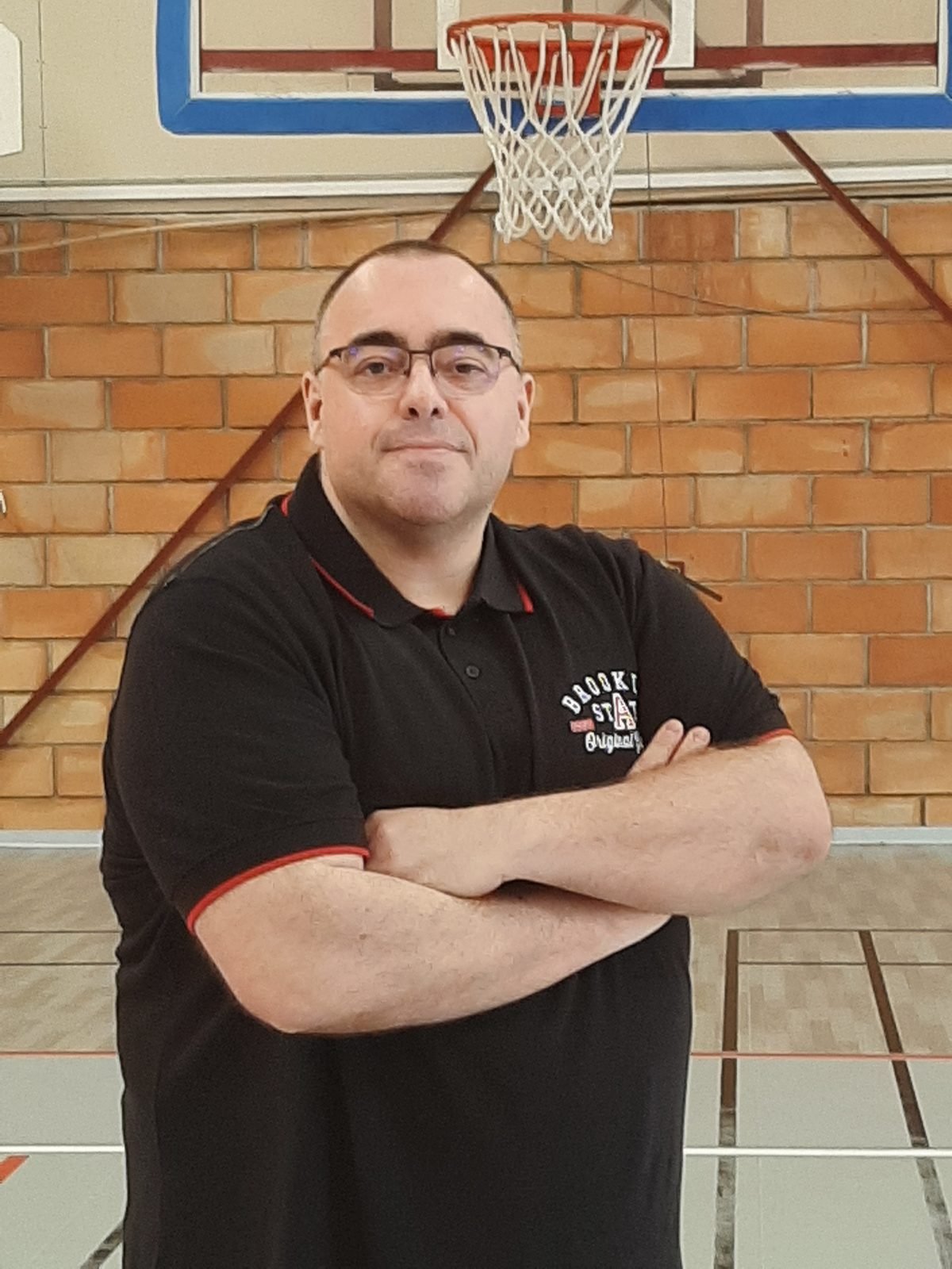 Portrait de Jérôme Guillermin, préparateur mental basket, bras croisés devant un panier